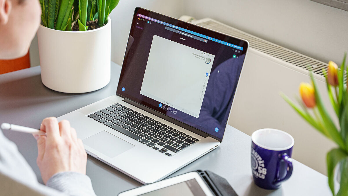 Schreibtisch mit Laptop, Tablet und einer Tasse