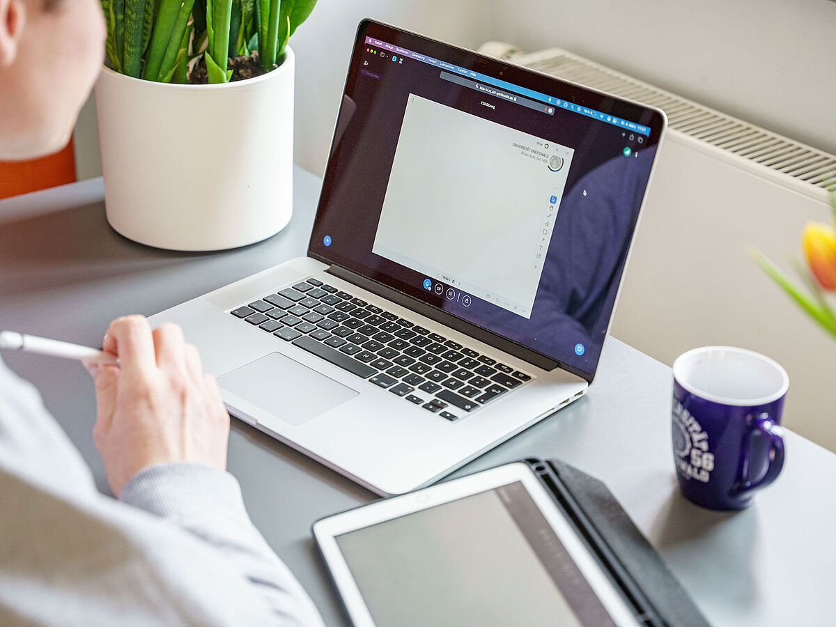 Schreibtisch mit Laptop, Tablet und einer Tasse
