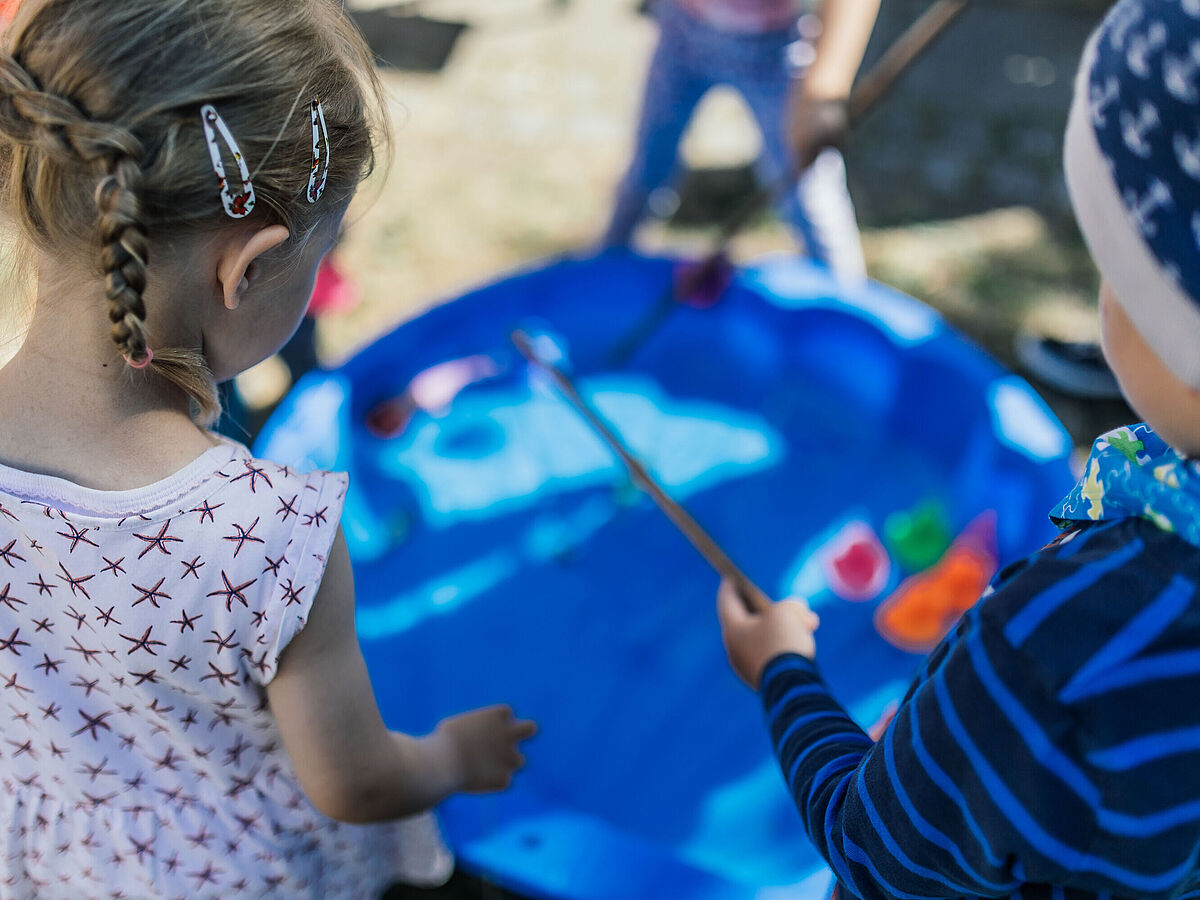 Es sind ein kleines Mädchen und ein kleiner Junge von hinten zu sehen.