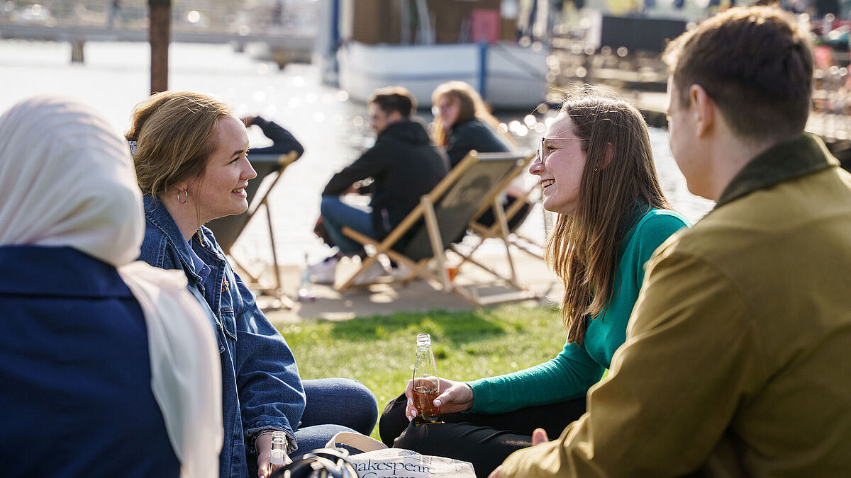 Studierende sind gemeinsam am Hafen und unterhalten sich