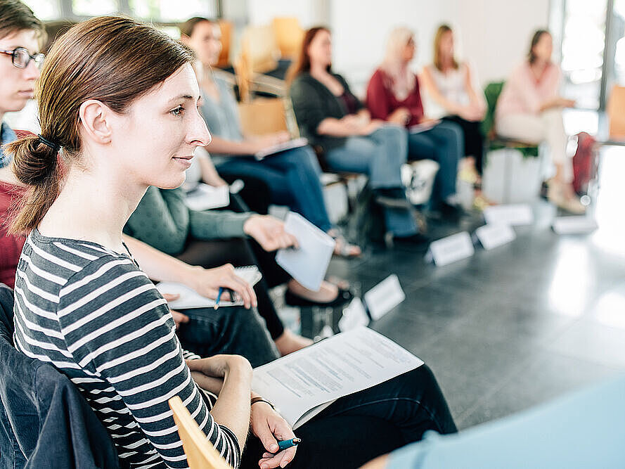 Eine große Gruppe Absolventinnen sitzt während eines Seminars zusammen.